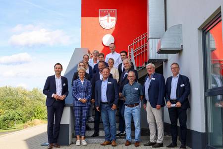 Landrat Sebastian Schuster (2.v.r.), Bürgermeister Lutz Wagner (8.v.r.), Schulleiterin Alexandra Weber (14.v.r.) und Michael Weber (TuS 05 Oberpleis, 9.v.r.), zusammen mit Ministerin Dorothee Feller (13 v.r.) mit allen Teilnehmenden des Besuches in Oberpleis.
