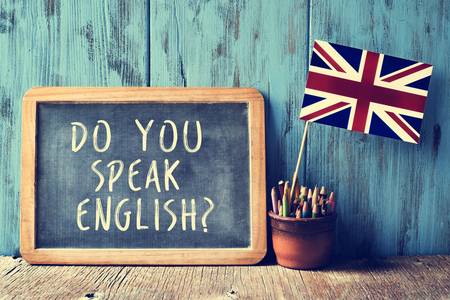 Tafel mit "Do you speak english" und britischer Fahne im Hintergrund