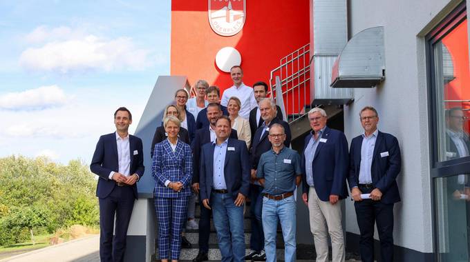 Landrat Sebastian Schuster (2.v.r.), Bürgermeister Lutz Wagner (8.v.r.), Schulleiterin Alexandra Weber (14.v.r.) und Michael Weber (TuS 05 Oberpleis, 9.v.r.), zusammen mit Ministerin Dorothee Feller (13 v.r.) mit allen Teilnehmenden des Besuches in Oberpleis.
