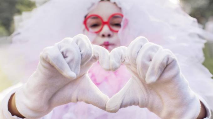 adobestock 168835660 girl in carnival costume makes heart from fingers