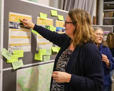 Eine Teilnehmerin klebt einen Punkt auf eine Infowand