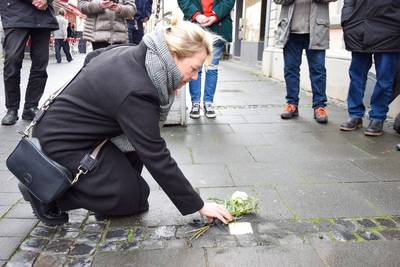 Bürgermeisterin Heike Jüngling kniet vor dem Stolperstein für Irmgard Stefanie Steinhardt in der Hauptstraße 380.
