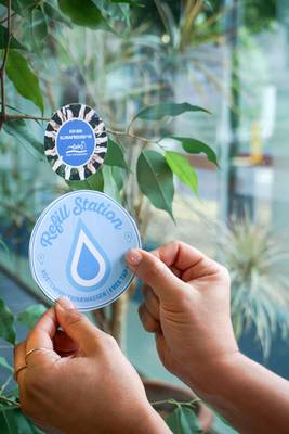 Die Refill-Aufkleber machen teilnehmende Betriebe sichtbar © Stadt Königswinter Aufkleber wird an Fenster geklebt