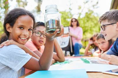 Eine Gruppe Kinder erarbeitet ein Projekt an einem Tisch in der Natur