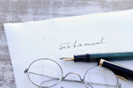 Symbolbild: Briefumschlag mit Aufdruck "Testament", Füller und Brille