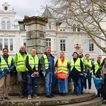 Das Team der Stadtverwaltung in Warnwestern und mit Zangen und Müllbeuteln vor dem Rathaus