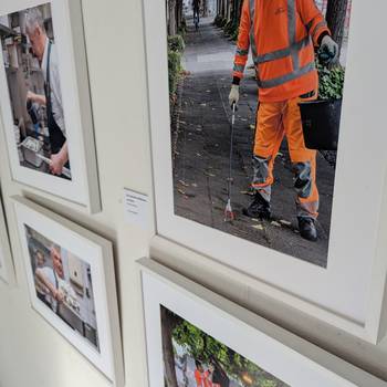 Vier Bilder der Ausstellung in weißen Rahmen an einer Wand