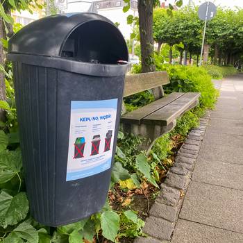 Aufkleber, die in mehreren Sprachen auf die richtige Nutzung der Mülleimer hinweisen