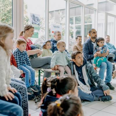 Väter und Kinder sitzen im Rathaus und nehmen am Familienprogramm teil