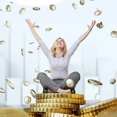 Eine Frau sitzt lachend auf einem Berg von Geld und streckt die Hände nach oben