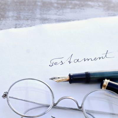 Symbolbild: Briefumschlag mit Aufdruck "Testament", Füller und Brille