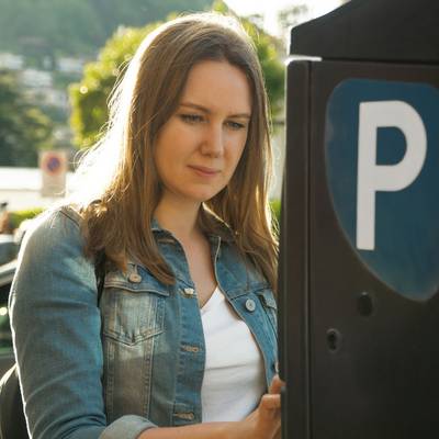 Eine Frau steht vor einem Parkautomaten