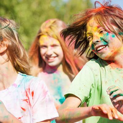 3 Kinder, die auf einem Holi-Fest mit farbigem Pulver beschmiert sind