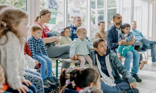 Väter und Kinder sitzen im Rathaus und nehmen am Familienprogramm teil