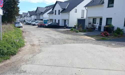Abbildung des Straßenzustands des Lilienwegs, im Hintergrund Häuser
