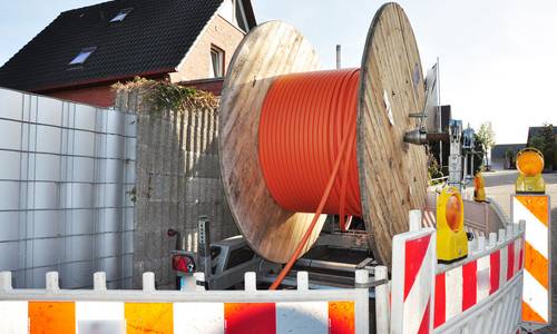 Eine Rolle mit Glasfaser steht auf einer Baustelle vor einem Haus