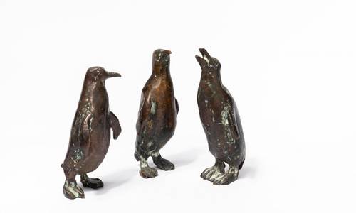 Drei Pinguine aus Bronze vor weißem Hintergrund