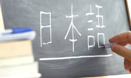 Japanische Schriftzeichen werden mit Kreide auf eine Tafel geschrieben