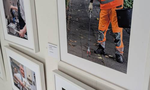 Vier Bilder der Ausstellung in weißen Rahmen an einer Wand