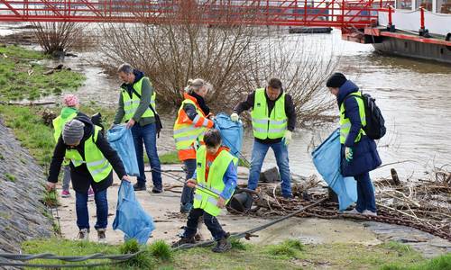 Am Rheinufer Königswinter-Altstadt wurde durch das Hochwasser Einiges angeschwemmt. Bürgermeister Lutz Wagner, Dezernentin Heike Jüngling und Mitarbeitende mit Kindern sammeln den Müll ein.