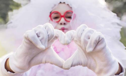 adobestock 168835660 girl in carnival costume makes heart from fingers