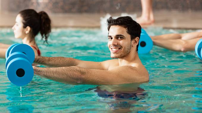 Ein Mann in einem Wassergymnastik-Kurs blickt freundlich in die Kamera
