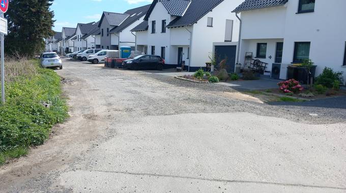 Abbildung des Straßenzustands des Lilienwegs, im Hintergrund Häuser