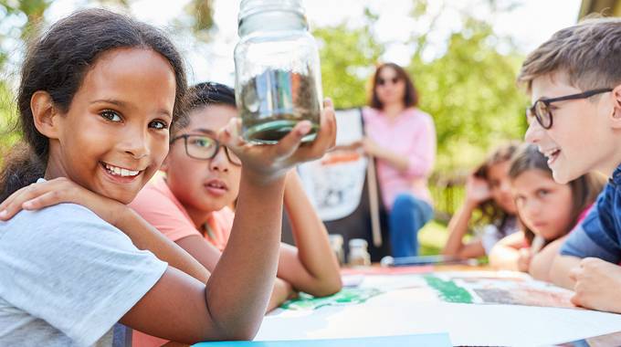 Eine Gruppe Kinder erarbeitet ein Projekt an einem Tisch in der Natur