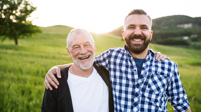 Zwei lachende Väter halten sich im Arm, im Hintergrund das Siebengebirge